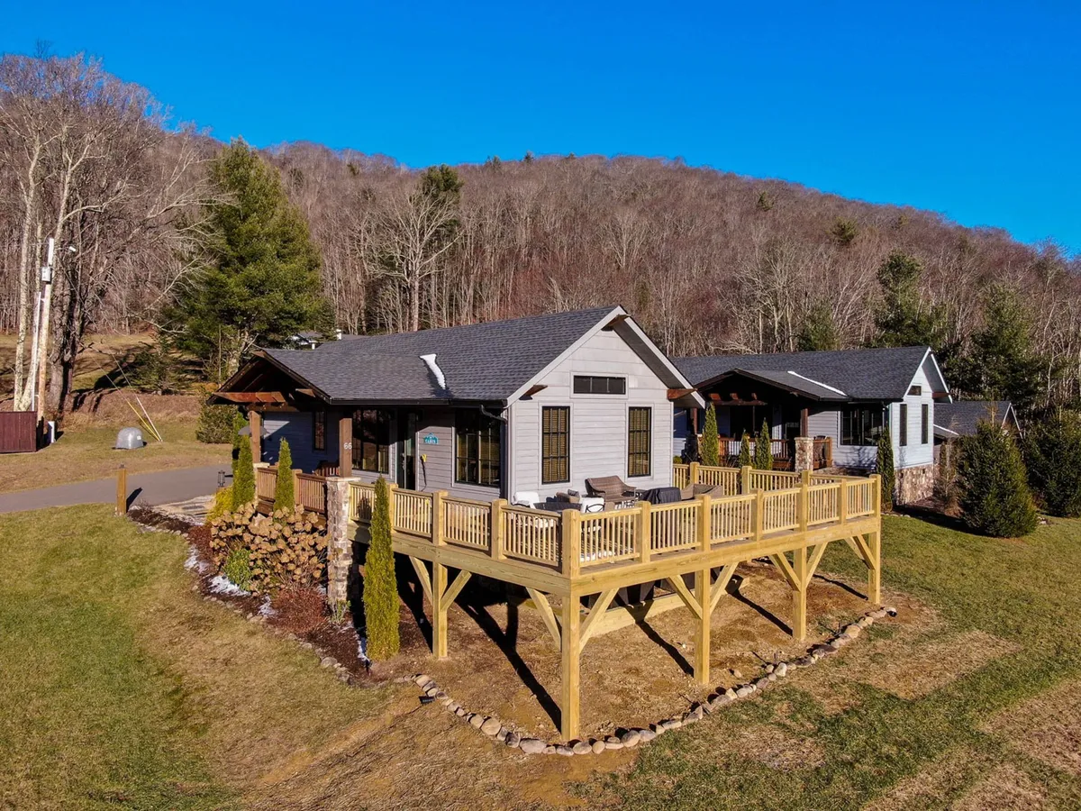 This image shows the home’s inviting exterior deck, set against a backdrop of lush greenery. The deck is arranged for outdoor relaxing and dining, with comfortable seating and the natural landscape unfolding beyond. The house’s facade is partially visible, providing context for the seamless transition between indoor comfort and outdoor adventure.