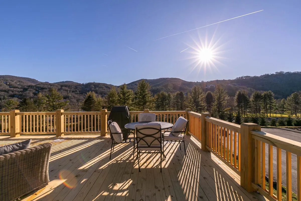 Deck seating bathed in sunshine, with a grill, comfortable chairs, and a stunning panorama of the mountains beyond. The image evokes a sense of warmth and an invitation to savor the fresh air, whether hosting a family gathering or stargazing at night.