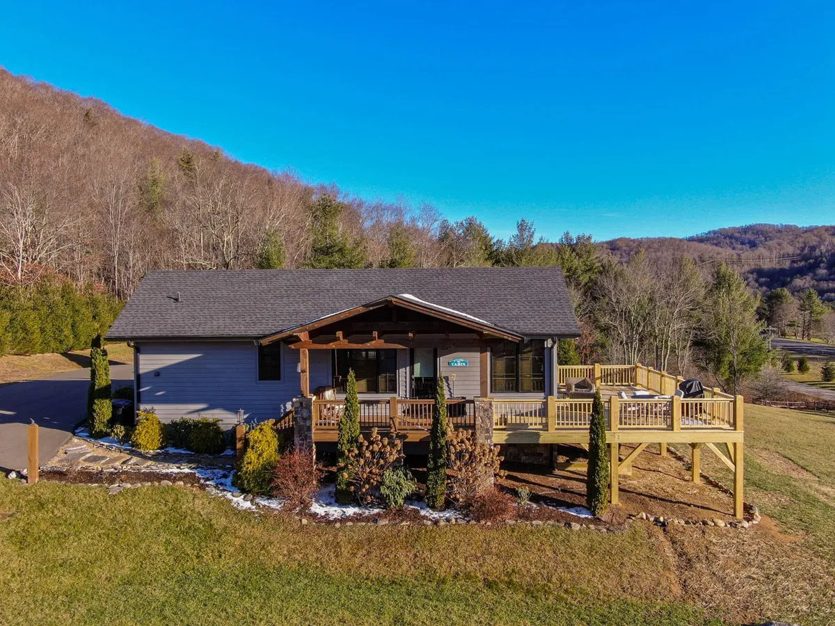 A tranquil wooden deck surrounded by tall trees and offering a clear mountain view. The deck is spacious and appears ready for outdoor gatherings, with ample room to relax and enjoy the fresh winter air. The natural landscape hints at the property's proximity to mountain activities and winter scenery.