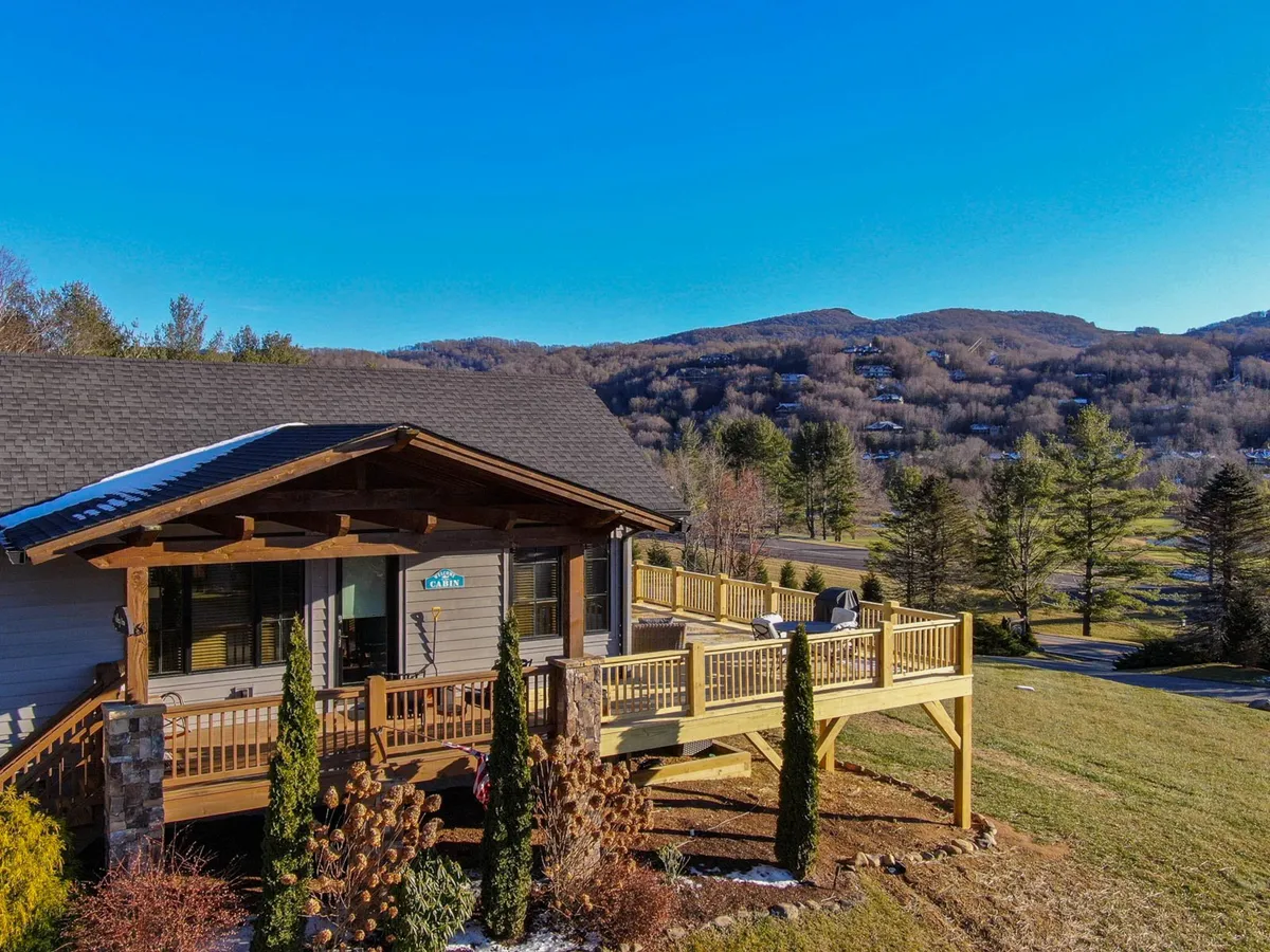 A wide view of the back deck overlooking the mountains, with visible landscaping and exterior structure. The space encourages gatherings and outdoor dining, with an emphasis on enjoying the view—be it for sunrise coffee, evening stargazing, or seasonal celebrations.